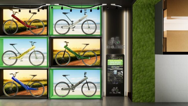 Seis bikes elétricas em vitrines luminosas com cenários de paisagem, ao lado da parede de musgo e do totem digital da Bici Eletric