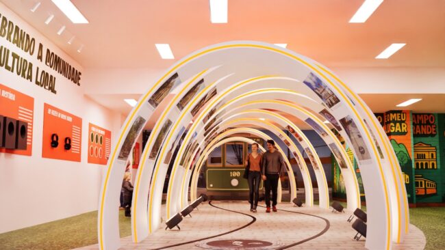 Túnel de arcos laranja com fotografias da exposição Campo Grande por Trás das Lentes, West Shopping, projeto da Unpack Design