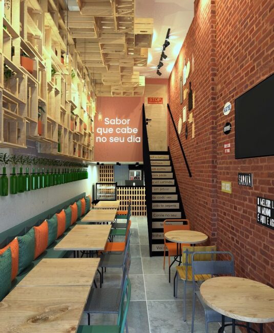 Interior do restaurante Vanilla Café & Comida com estantes de caixotes, garrafas verdes e banco com almofadas, projeto da Unpack Design